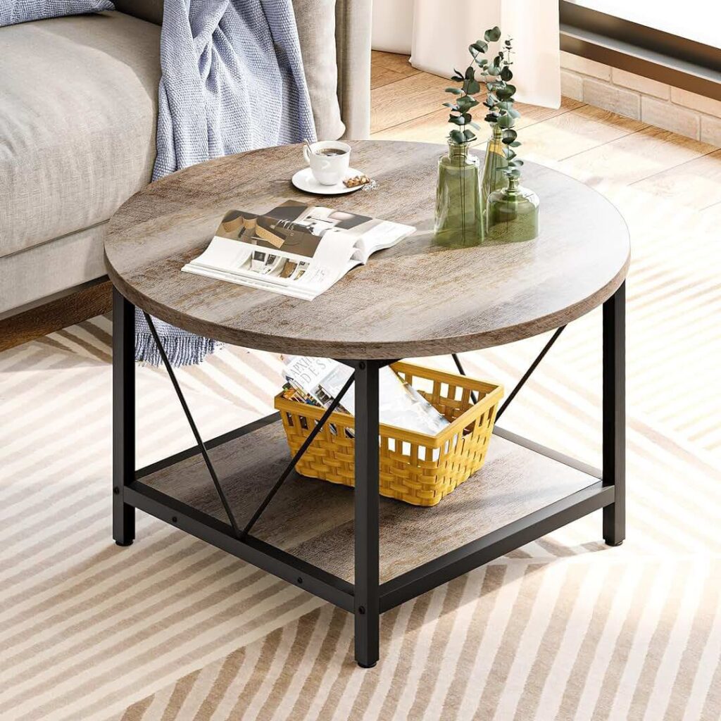 Round wooden coffee table with a black metal frame, decorated with green glass vases, a teacup, and an open magazine. A yellow basket with magazines is placed on the lower shelf beneath the table.