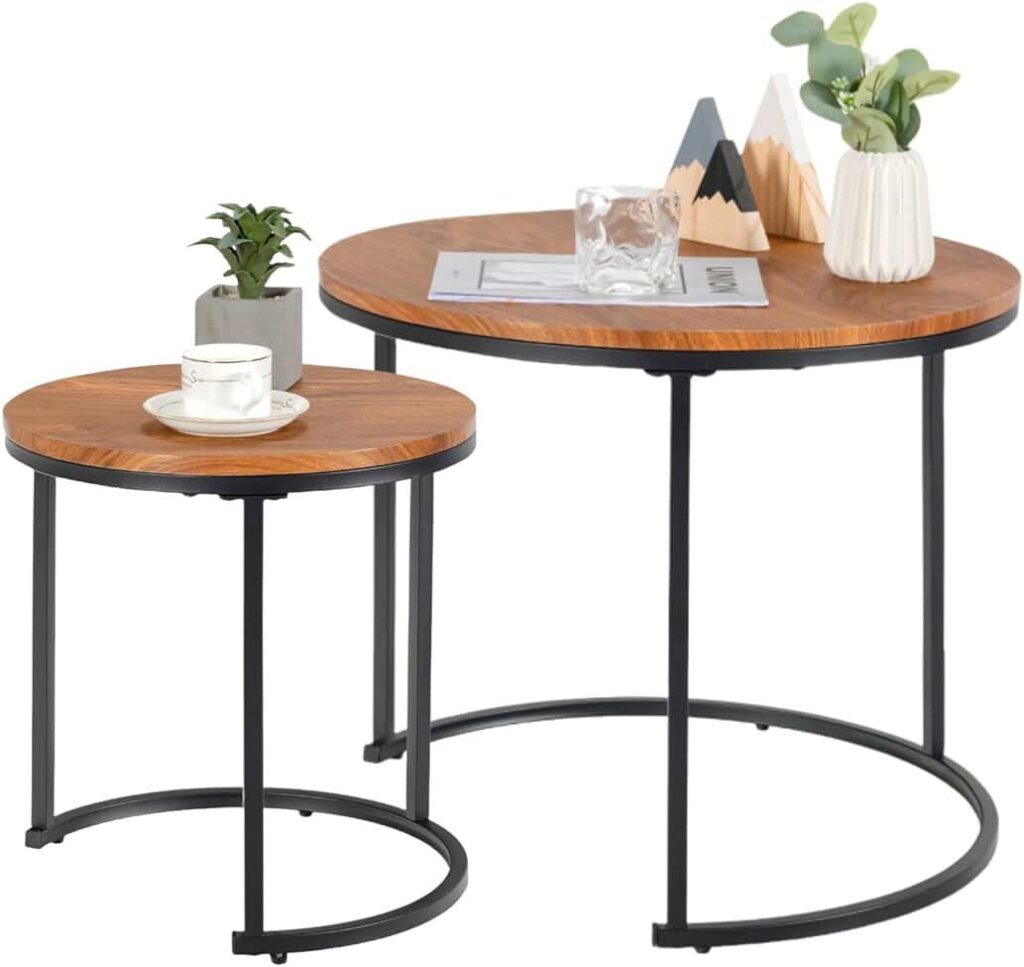 Two round wooden nesting coffee tables with black metal legs, featuring simple modern decor including a small plant, a glass cup, and geometric decorative pieces.