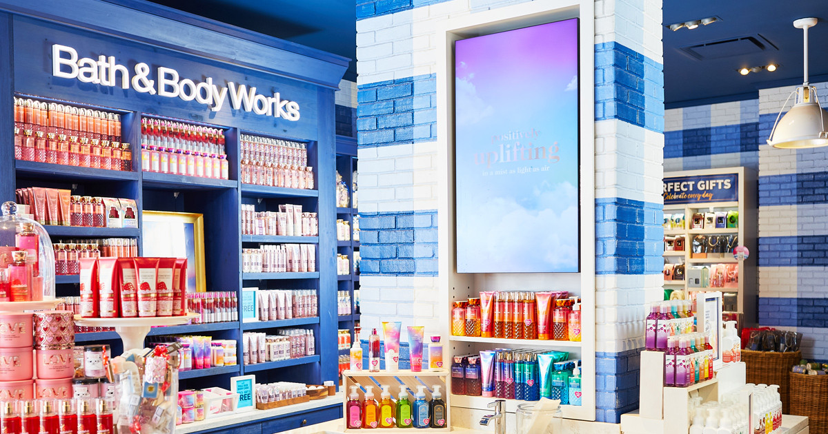 Interior of a store showcasing shelves filled with body lotions, fragrance mists, and candles, with vibrant displays and promotional signage.