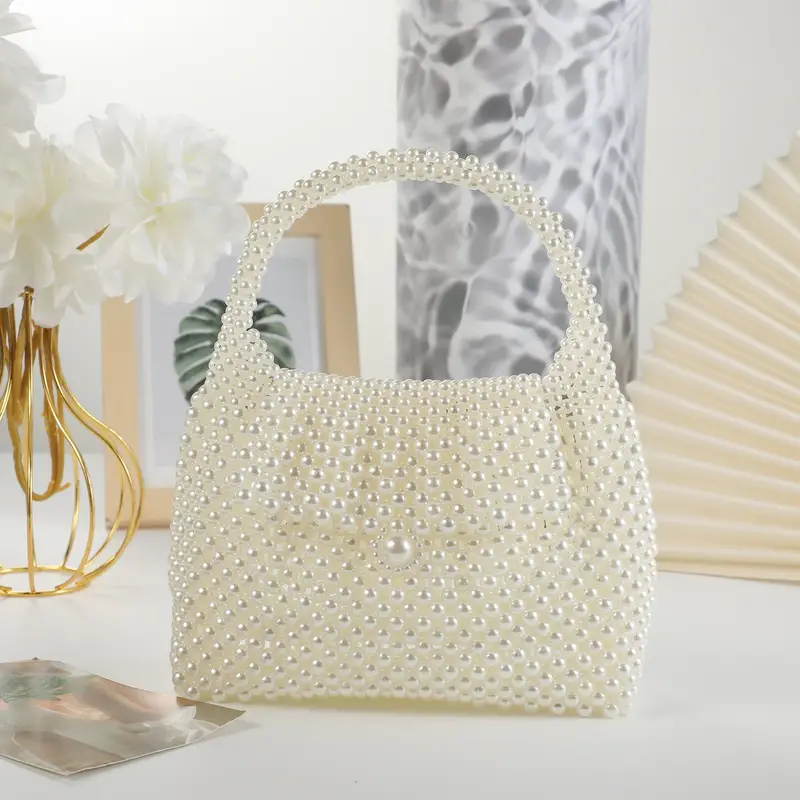 Elegant white beaded bag adorned with pearl-like beads, featuring a curved handle and a delicate button clasp, perfect for formal occasions and stylish events.