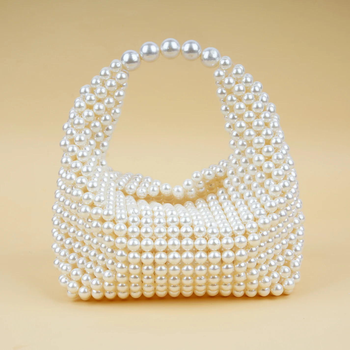 Chic beaded bag adorned with pearl-like beads, featuring a rounded handle and a structured design, perfect for adding an elegant touch to formal and casual outfits.