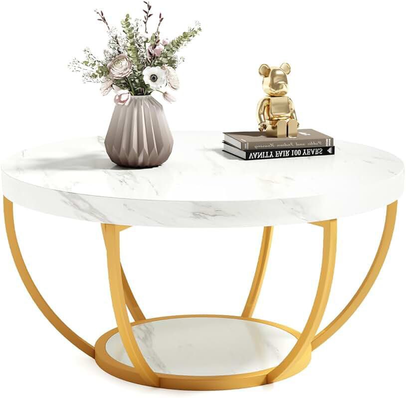 Round marble coffee table with gold curved metal legs, decorated with a vase of flowers and a small golden bear sculpture placed on top of stacked books.