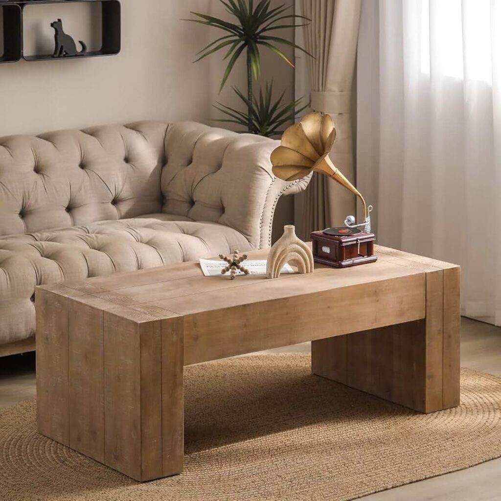 Rustic wooden coffee table in a cozy living room, decorated with a vintage gramophone and a ceramic vase. The table is placed on a woven jute rug in front of a tufted beige sofa, with a potted plant and soft curtains adding to the room's inviting ambiance.