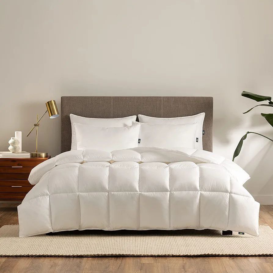 A modern bedroom featuring a gray upholstered bed frame with a luxurious white quilted duvet and matching pillows, paired with a stylish brass lamp and a wooden side table. Shop now and get this duvet on sale.