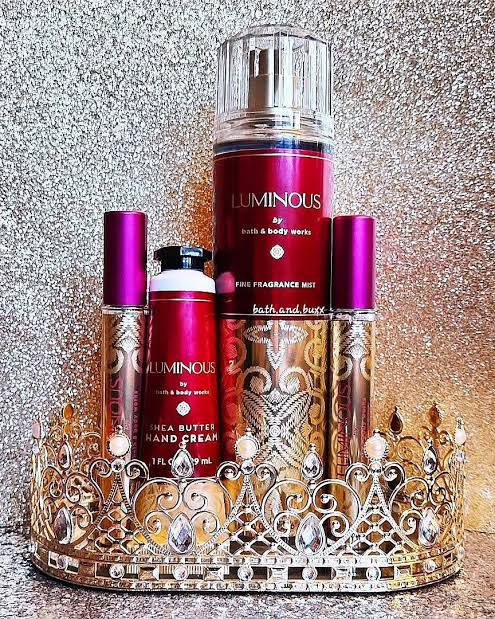 Bath and Body Works Luminous collection featuring fragrance mist and shea butter hand cream, elegantly arranged with a decorative crown on a glittery background.