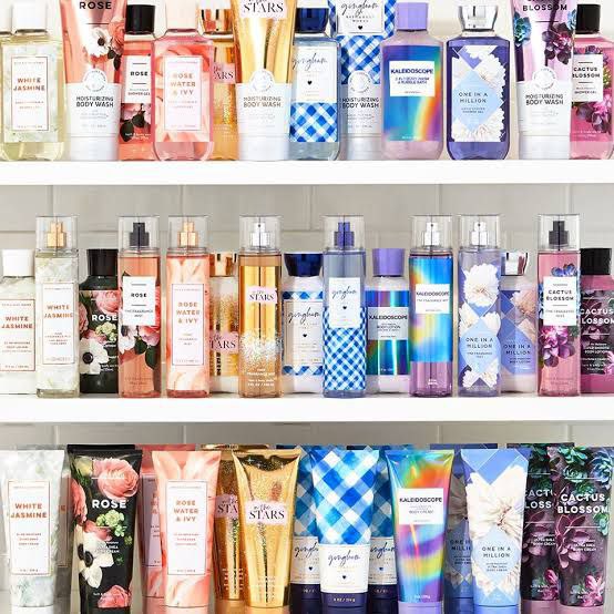 A collection of Bath and Body Works body lotions, fragrance mists, and body creams displayed on shelves, featuring a variety of floral and seasonal scents.