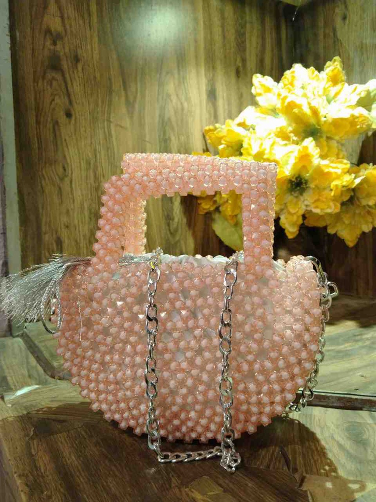 Pink beaded bag with a rounded shape, embellished with a silver chain strap and tassel detail, offering a playful yet elegant accessory for casual outings.